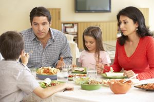 Young Hispanic Family Enjoying Meal At Home