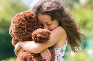 child hugging teddy bear